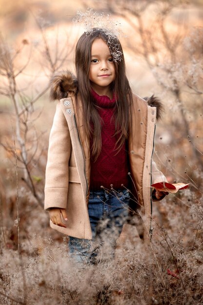 Portret van een schattig lachend meisje dat speelt met gevallen herfstbladeren