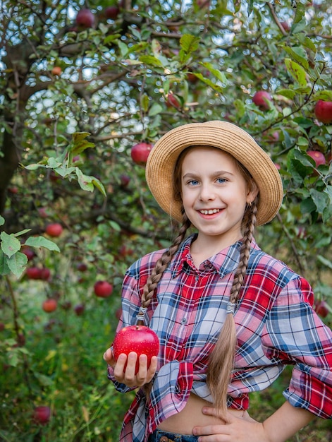 Portret van een schattig meisje in een boerderijtuin met een rode appel Herfstoogst van appels
