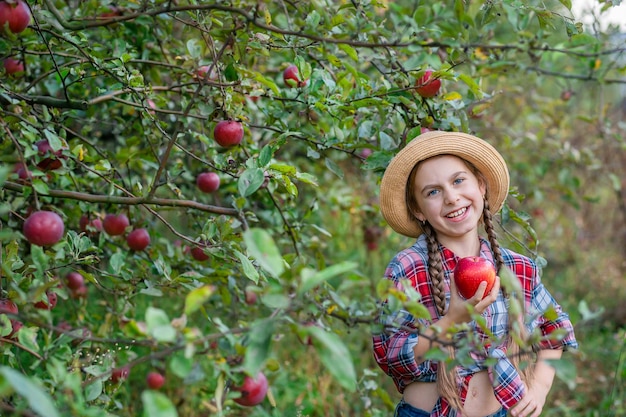 Portret van een schattig meisje in een boerderijtuin met een rode appel Herfstoogst van appels