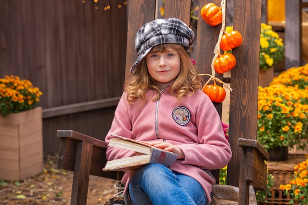 portret van een schattig meisje met een boek in de herfst bij het huis