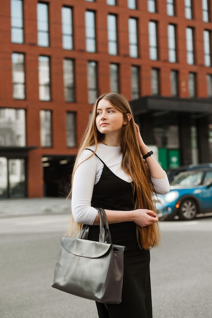 Portret van een schattig meisje met lang blond haar staat op een achtergrond van stadsgezicht