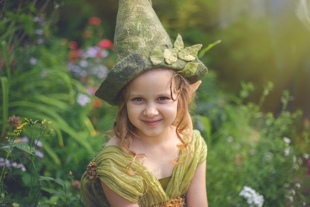 Portret van een schattig mooi meisje in een kabouterhoed en kostuum in groen bos.