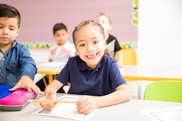 Portret van een schattig spaans meisje dat naar de kleuterschool gaat en lacht met een tandeloze grijns