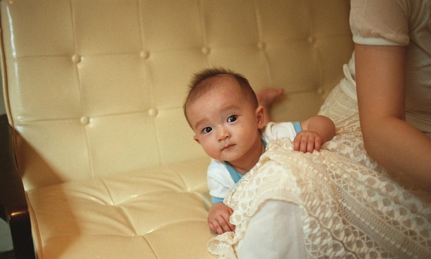 Foto portret van een schattige baby door moeder op de bank thuis