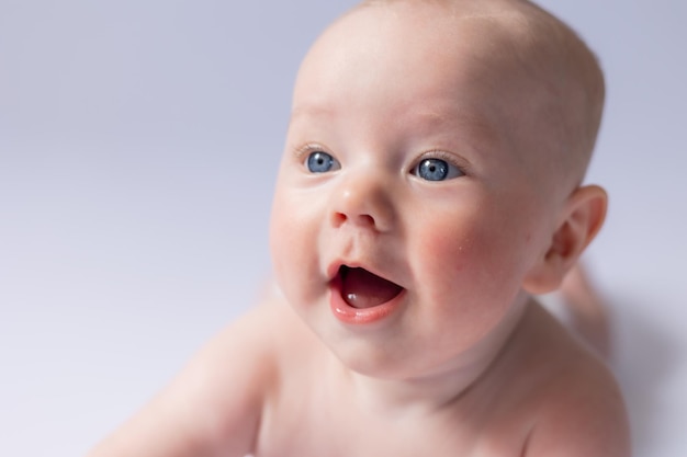 Foto portret van een schattige baby maanden oud op een witte achtergrond in de studio die glimlachend naar de camera kijkt