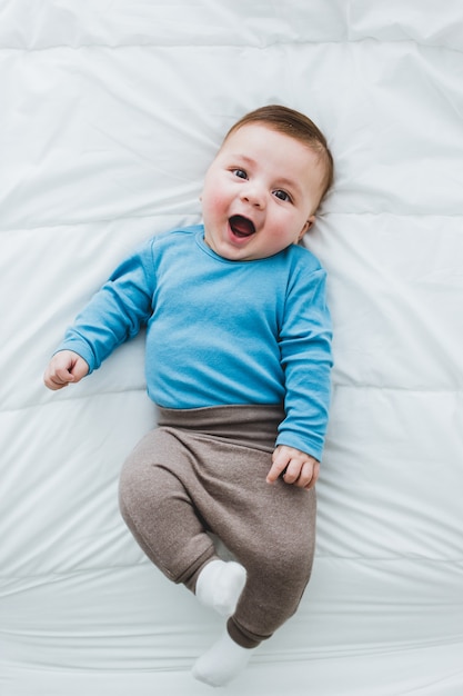 Portret van een schattige baby van 3 maanden die lacht in een bed van witte lakens