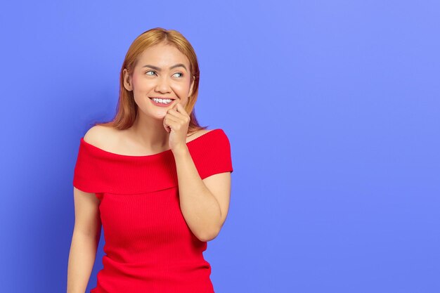 Portret van een schattige blonde Aziatische jonge vrouw die emotioneel geschokt is omdat ze ideeën heeft die op een paarse achtergrond zijn geïsoleerd