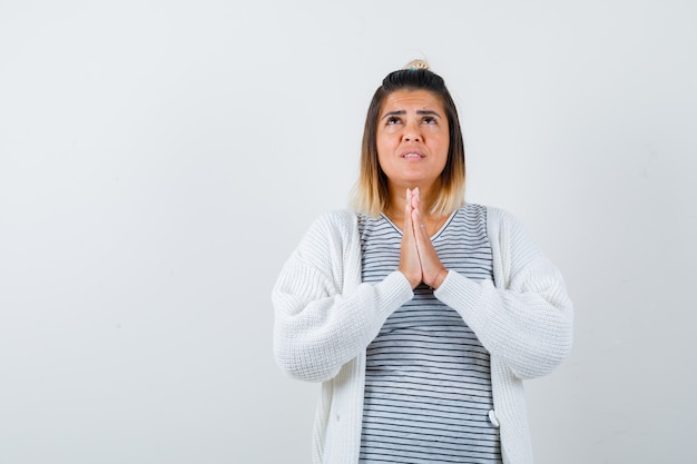 Portret van een schattige dame die de handen in een gebedsgebaar houdt in t-shirt, vest en er hoopvol vooraanzicht uitziet