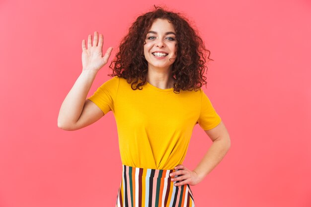 Portret van een schattige gelukkig mooie jonge krullende vrouw poseren geïsoleerd op rode muur.