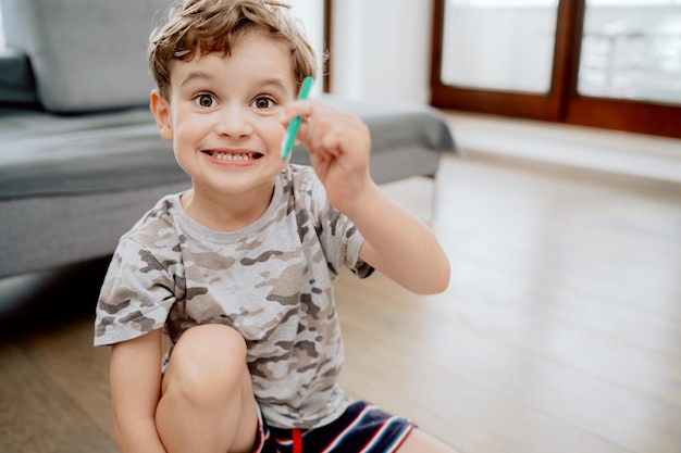 Portret van een schattige, gelukkige schoolgaande jongen zittend op de houten vloer in de woonkamer