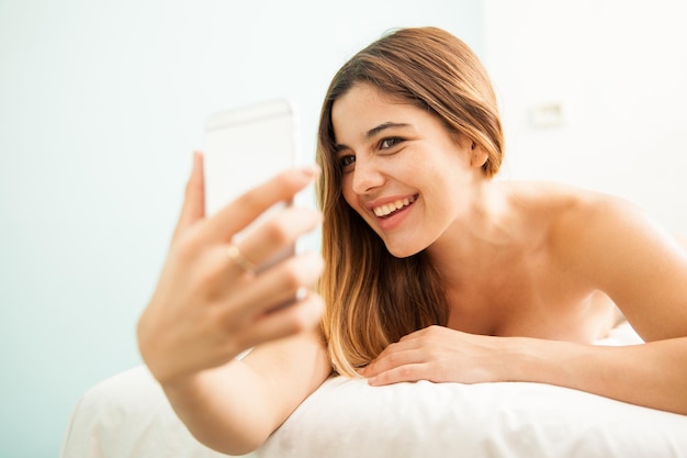 Portret van een schattige jonge vrouw die plezier heeft en een selfie maakt terwijl ze verwend wordt in een gezondheidskliniek en spa