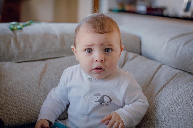 Portret van een schattige jongen die thuis op de bank in de woonkamer zit