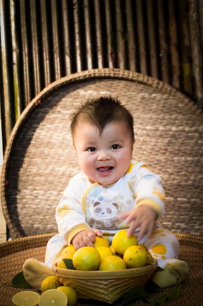 Portret van een schattige jongen met citroenen op een rieten stoel
