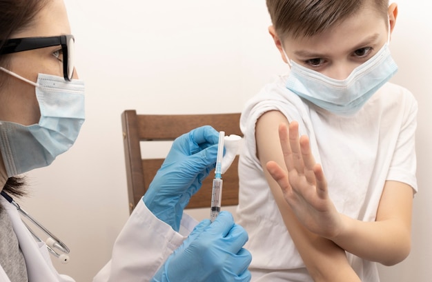 Portret van een schattige kleine jongen die wordt gevaccineerd bij de dokter