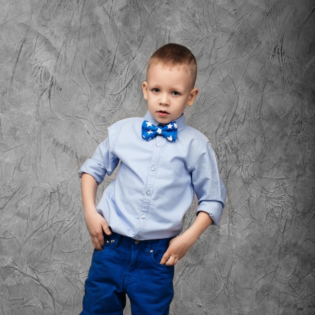 Portret van een schattige kleine jongen in spijkerbroek, blauw shirt en vlinderdas