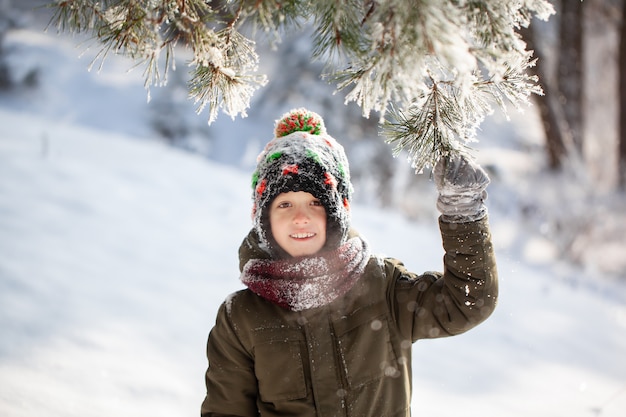 Portret van een schattige kleine jongen in warme kleren buiten spelen tijdens sneeuwval in zonnige winterdag.