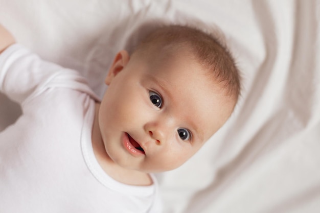 Portret van een schattige lachende pasgeboren baby in een witte Romper op een witte achtergrond close-up. producten voor kinderen. concept van gelukkige jeugd en moederschap. kinderopvang. Hoge kwaliteit foto