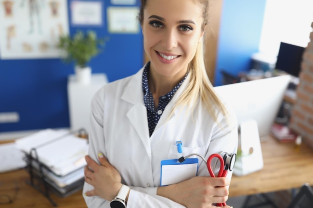 Portret van een schattige medische werker of hoofdarts in uniform poseren in het kantoor van de kliniek. gekwalificeerde vrouwelijke specialist in geneeskunde. gezondheidszorg, afspraakconcept