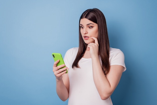 Portret van een schattige, mooie dame met een telefoonscherm op een blauwe achtergrond