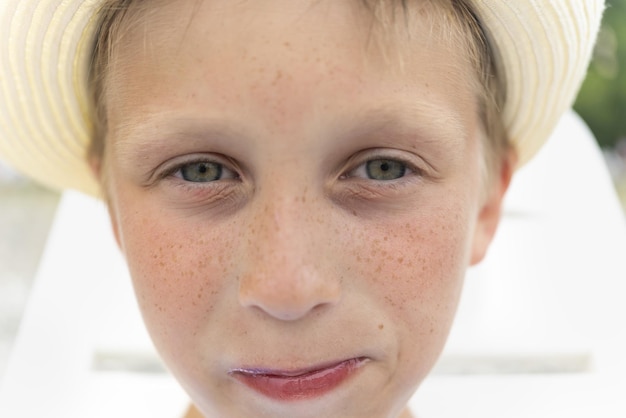 Portret van een schattige, mooie jongen in een hoed met sproeten die een jongen sluit met een serieuze en droevige blik en