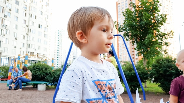 Portret van een schattige peuterjongen die op de speelplaats van de kinderen staat