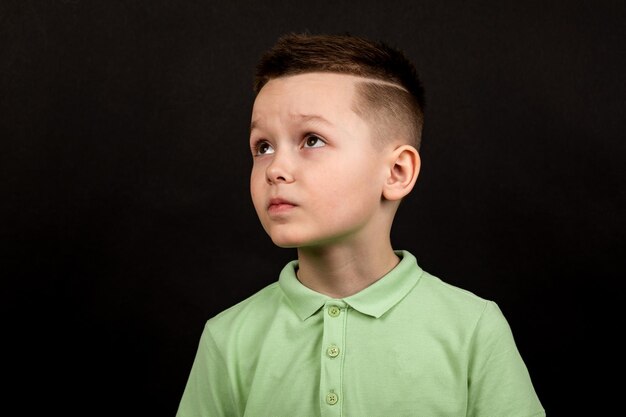 Portret van een schattige tiener die een groen t-shirt draagt op zwarte achtergrond