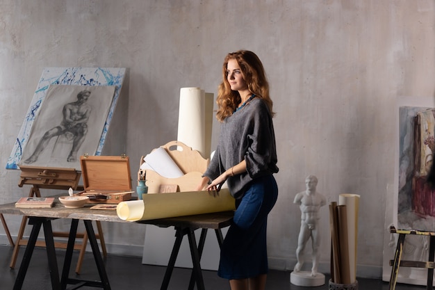 Foto portret van een schitterende vrouwelijke kunstenaar die aan kunstproject aan haar studio werkt