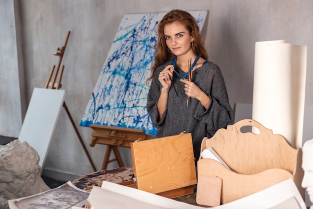 Portret van een schitterende vrouwelijke kunstenaar die aan kunstproject aan haar studio werkt