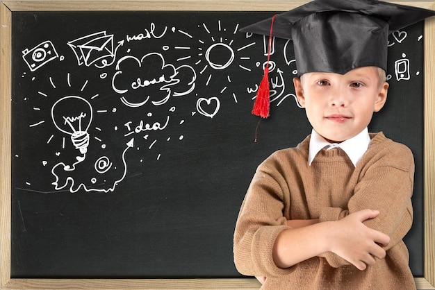 Portret van een schooljongen met een grote ronde bril en academische hoed in een klaslokaal.