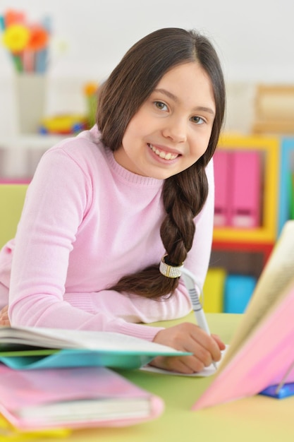 Portret van een schoolmeisje dat huiswerk maakt in haar kamer