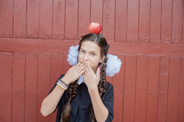 Portret van een schoolmeisje dat zich met appel op hoofd bevindt