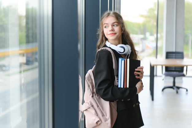 Foto portret van een schoolmeisje op school ze houdt boeken in haar handen onderwijsconcept