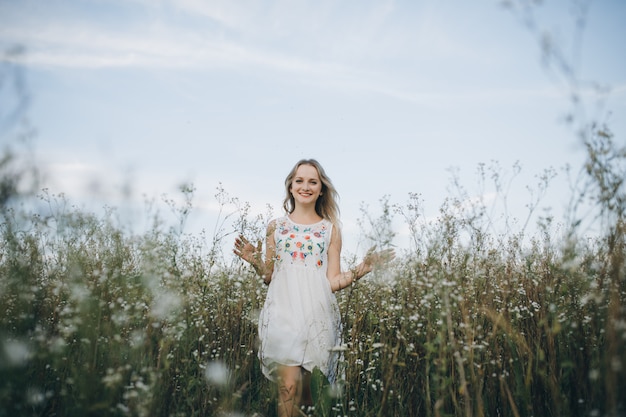 Portret van een schoonheid blonde meisje met blauwe ogen en lang haar op haar hoofd lopen in veld met witte bloemen