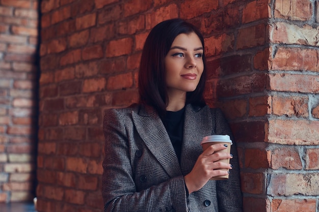 Portret van een schoonheidszakenvrouw houdt een kopje koffie in de ochtend vast