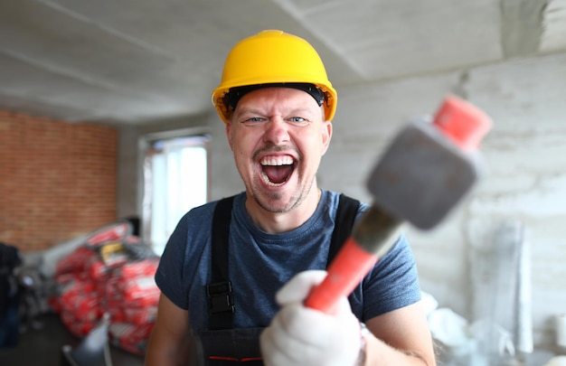 Portret van een schreeuwende man die een groot stevig bouwgereedschap vasthoudt