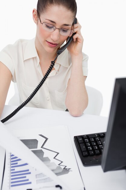 Portret van een secretaresse die een telefoongesprek maakt terwijl het bekijken van statistieken