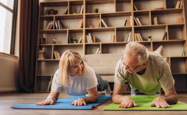 Portret van een senior koppel doet gymnastiek en yoga rekoefeningen samen thuis op zonnige ochtend concept van gezonde levensstijl fitness recreatie paar doelen welzijn en pensioen