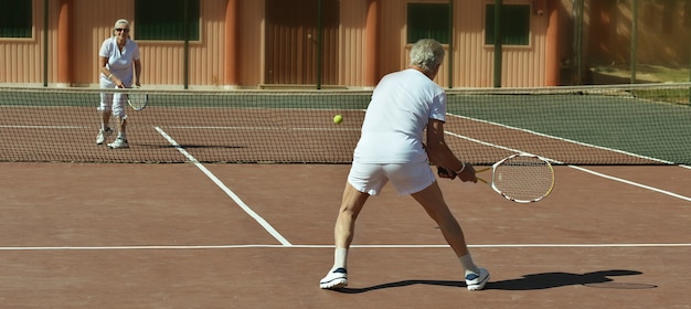 Portret van een senior koppel op tennisbaan