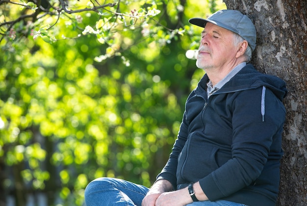 Portret van een senior man buiten zittend op een bankje in het park optimisme goede gezondheid expressie pensioen of pensioen concept