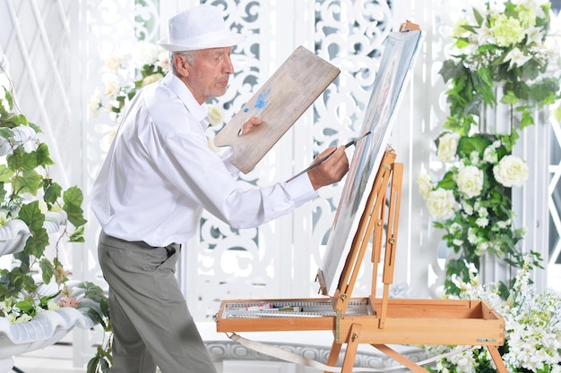 Portret van een senior man die een foto maakt in een lichte kamer