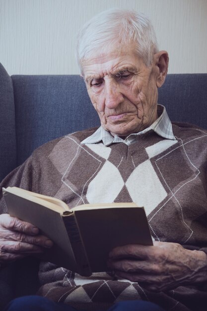 Foto portret van een senior man die in een fauteuil zit en boeken leest. vrije tijd oude man