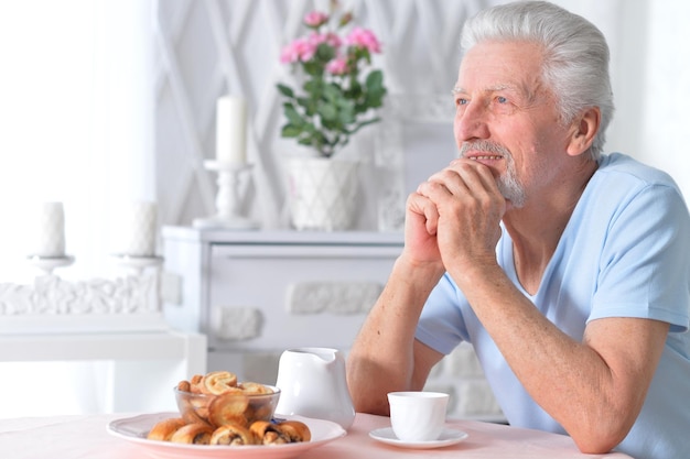 Portret van een senior man die thuis ontbijt