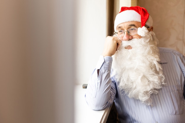 portret van een senior man met een kerstmuts die naar de camera kijkt