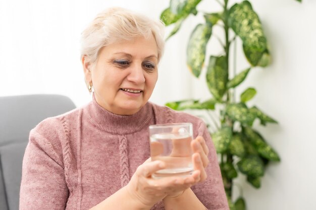 Portret van een senior vrouw die een glas water drinkt.