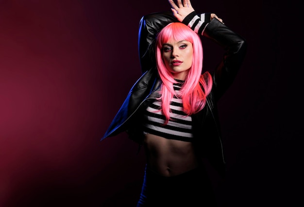 Portret van een sensueel schoonheidsmodel met een roze haarpruik en een rockerjack dat over de achtergrond staat met donkere schaduwen en licht. sexy stijlvolle vrouw met punk trendy modeartikelen die pose doen.