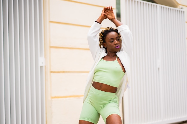 Portret van een sensuele Afrikaanse vrouw met sportieve kleding die op straat danst