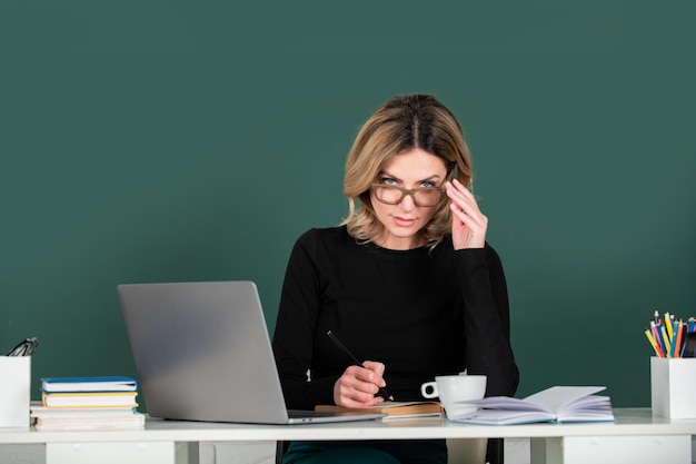 Portret van een serieuze, geconcentreerde leraar of vrouwelijke tutor die aan tafel werkt op de universiteit of op de middelbare school Jonge vrouwelijke student die in de klas studeert