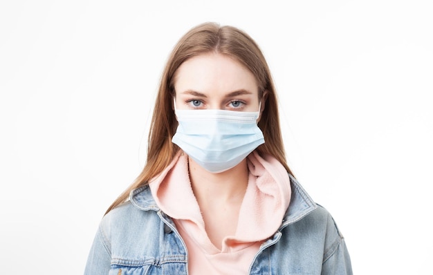 Portret van een serieuze jonge vrouw met een medisch masker dat op een witte achtergrond wordt geïsoleerd