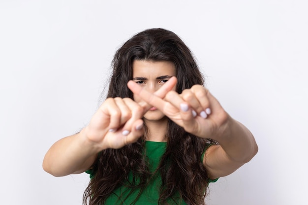 Portret van een serieuze jonge vrouw met een stopgebaar met haar handpalm op een witte achtergrond