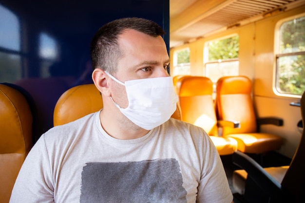 Portret van een serieuze man die in de trein zit en vooruitkijkt met een gezichtsbeschermend masker om de luchtwegen te beschermen tegen coronavirusinfectie covid19 Preventieve maatregel Nieuw normaal concept